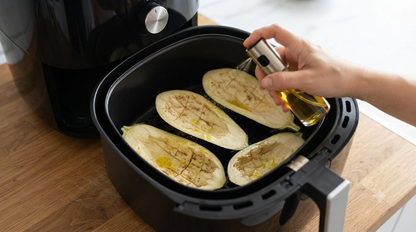 Mitades de berenjena precocinándose en la cesta de la freidora de aire