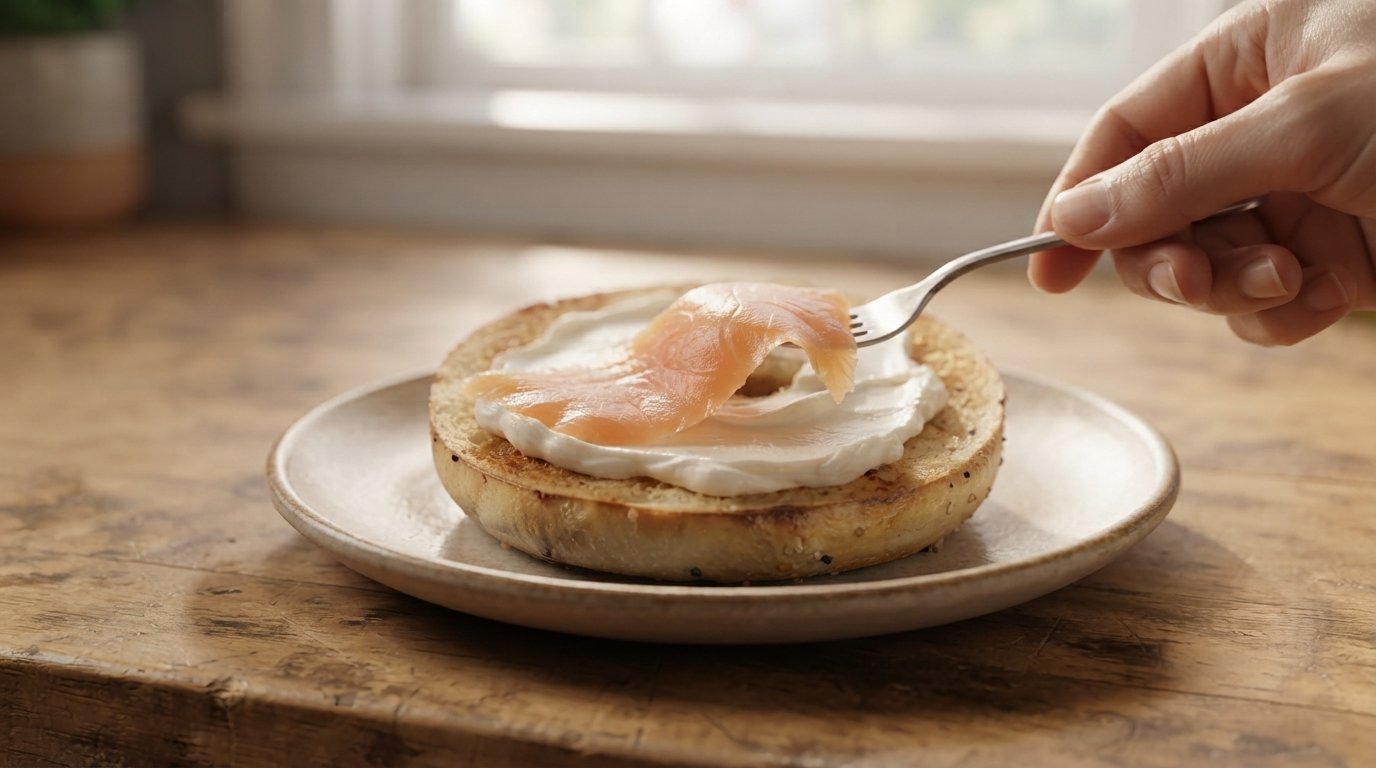 Salmón ahumado siendo colocado sobre la capa de queso crema