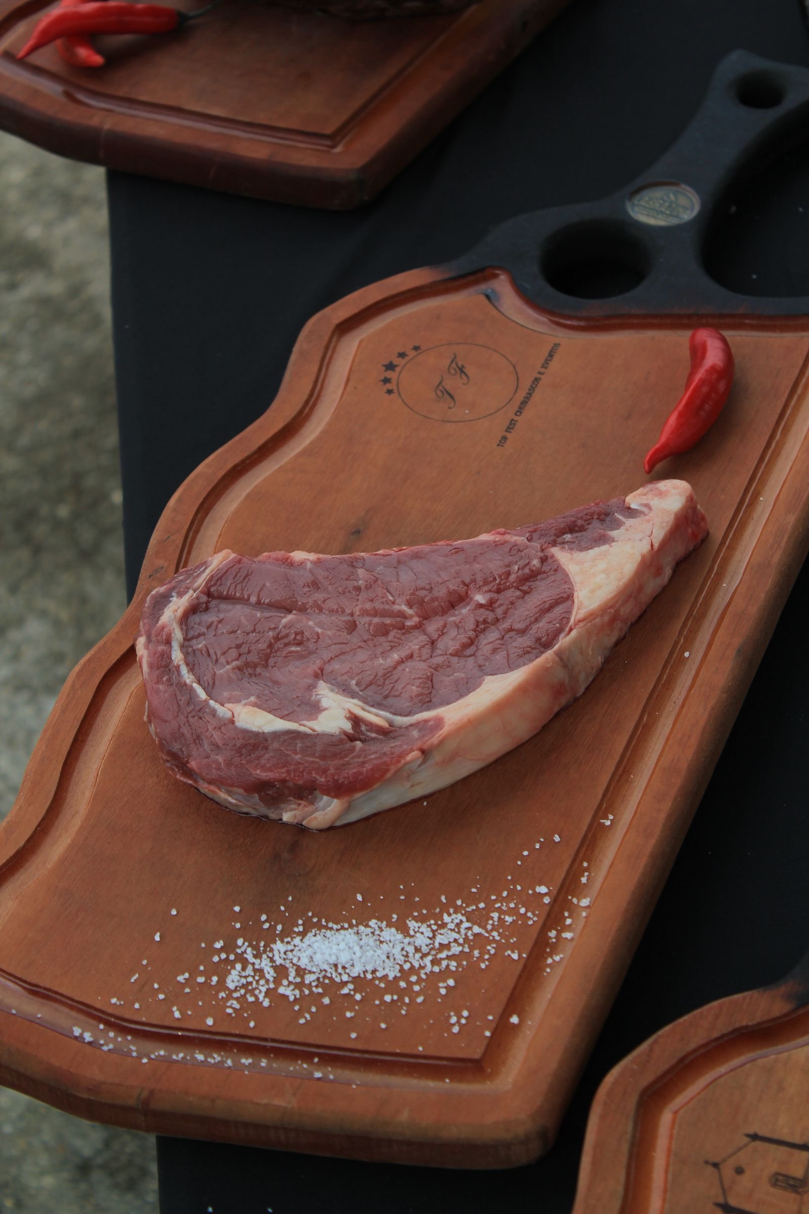 Entrecot de ternera crudo sobre tabla de madera con sal y pimienta