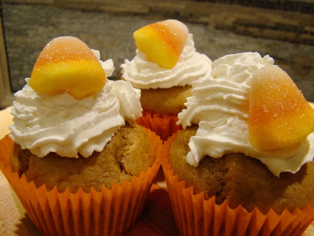 Muffins de calabaza decorados con nata y caramelo naranja (foto de archivo)
