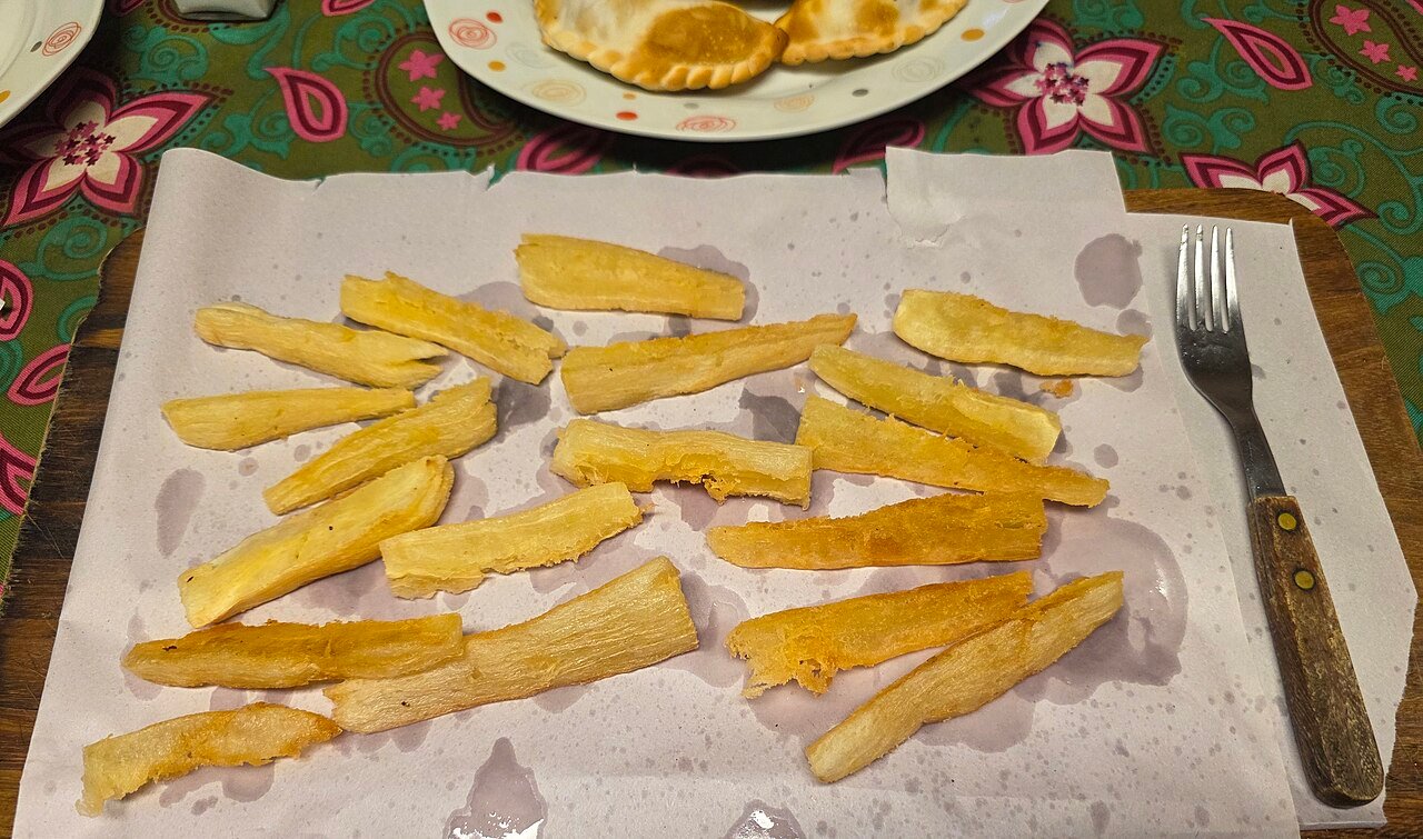 Yuca (mandioca) frita servida sobre una tabla de madera, foto de archivo